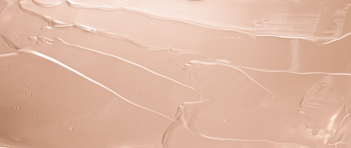 close-up of a cream cleanser smear on a pale blush surface