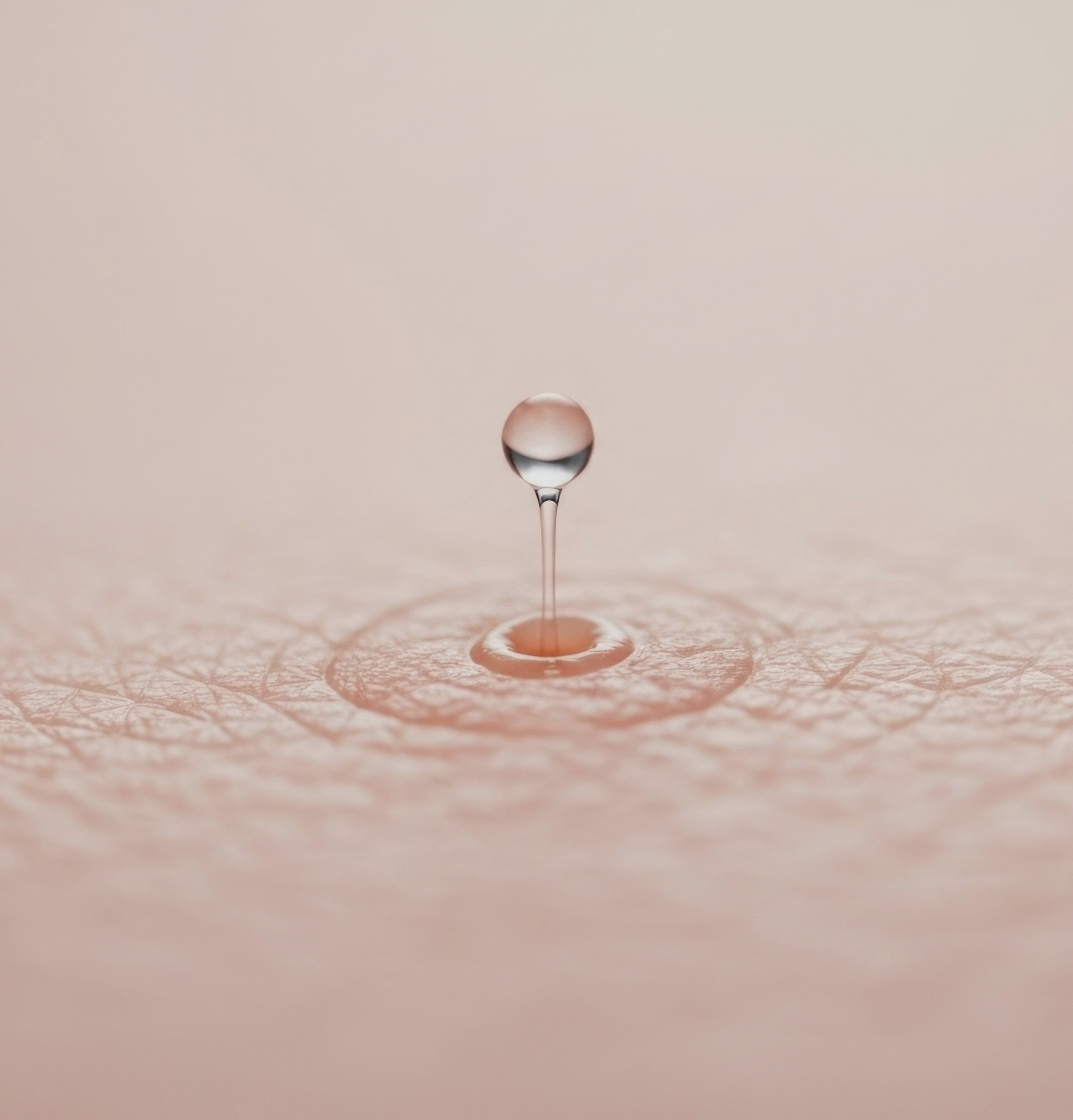 Close-up of a water droplet falling onto a surface with ripples.