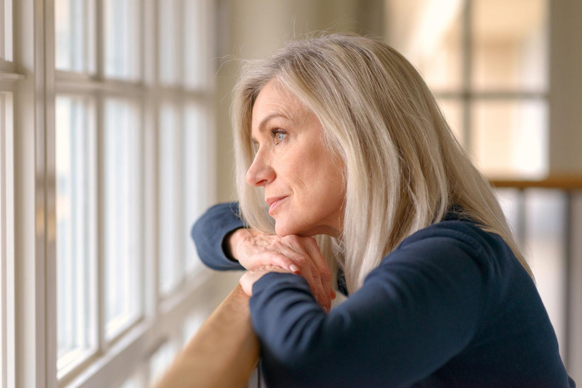 A woman resting at a window, looking outward — unhurried, attentive, still thinking.