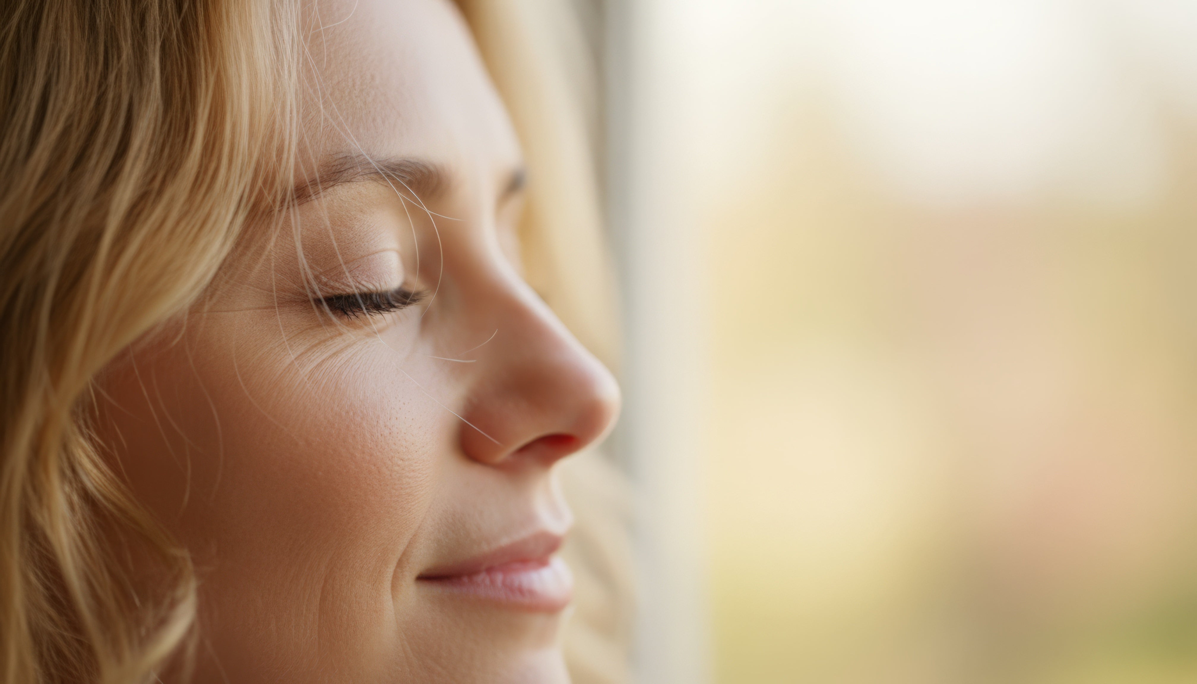Close-up of a woman with closed eyes, blurred background